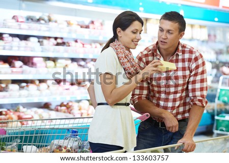 Young Family people choosing bio food cheese in grocery supermarket during weekly shopping