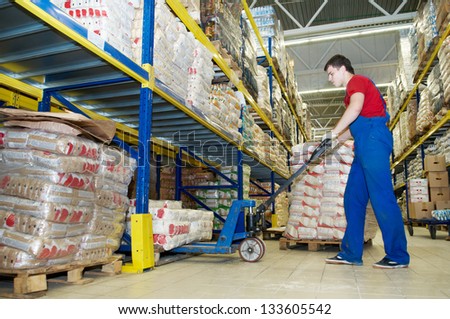 worker with fork pallet truck stacker in warehouse loading Group of food packages