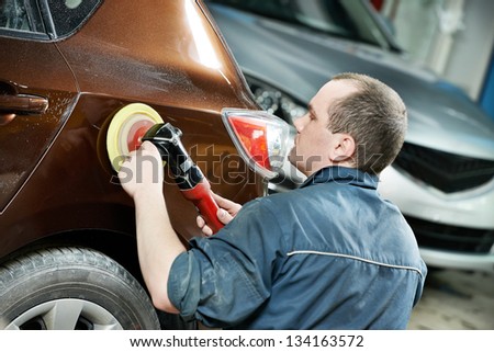 auto mechanic worker polishing bumper car at automobile repair and renew service station shop by power buffer machine