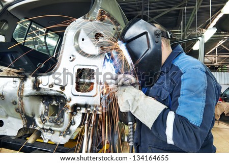Professional Repairman Worker In Automotive Industry Welding Metal Body Car With Sparks