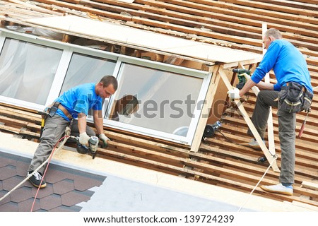 worker on roof at works with flex tile material mounting roofing