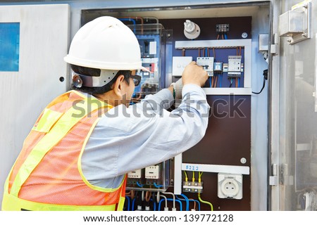 One chinese electrician builder at work with high voltage power electric line distribution fuseboard