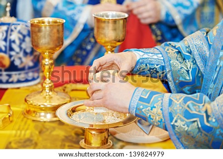 Christian sacrament. Hands of priest refracting bread during orthodox liturgy ceremony