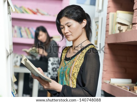 Chinese young college student girl in a library with books during self education