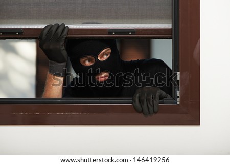 Thief Burglar opening window during house breaking