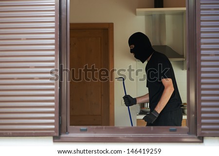 Thief Burglar opening metal door with a crowbar during house breaking