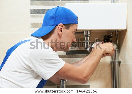 Young plumber worker working with spanner at sanitary washbasin installation system