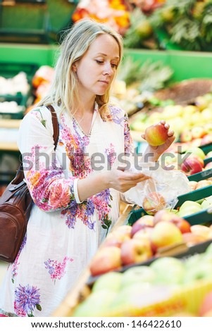 Woman choosing bio food fruit apple in vegetable supermarket during shopping