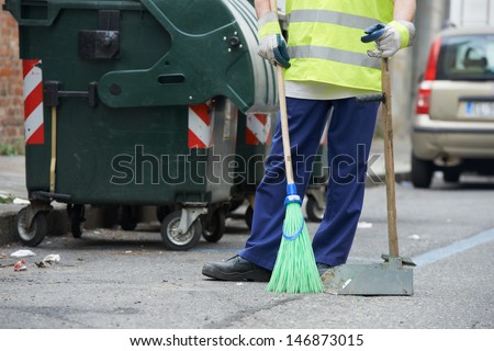 Process of urban street cleaning sweeping. Worker with broom and dust pan