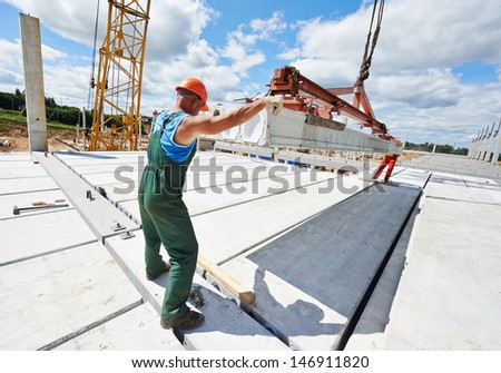 builder worker in safety protective equipment installing concrete floor slab panel at building construction site