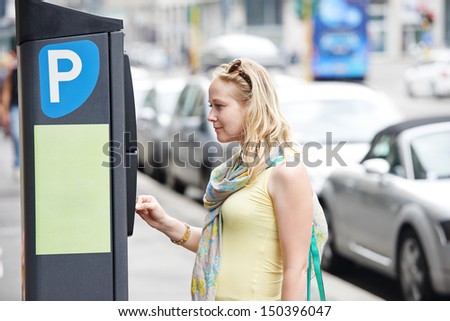 Young female woman paying for parking in the street