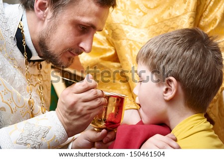 Orthodox Euharist ceremony. Priest makes child communion with bowl in church