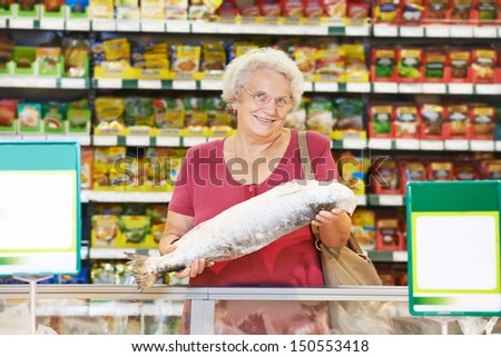 Aged smiling woman choosing bio food fruit grape in vegetable store or supermarket