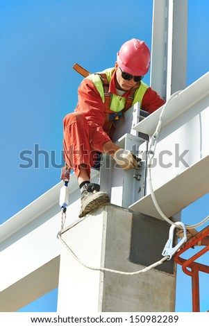 worker in uniform and safety protective equipment at metal construction frames installation and assemblage