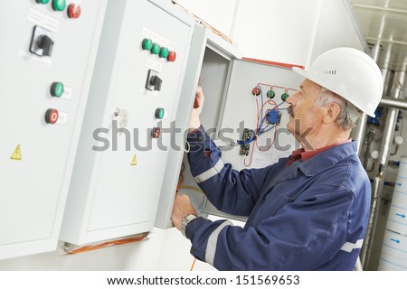 senior adult electrician builder engineer testing equipment in fuse box