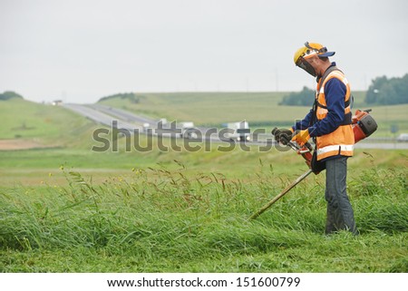 lawn mower worker man cutting grass in green field
