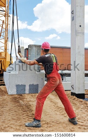 worker in safety protective equipment installing concrete floor slab panel at building construction site