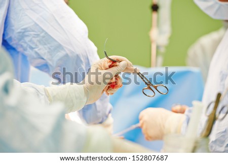 Hand of surgeon and assistant with surgery tool during surgical treatment