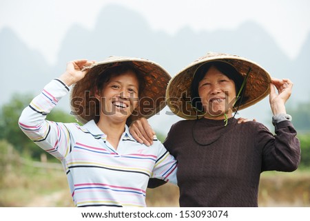 Smiling chinese asian women workers at farm work gathering citrus oranges in agriculture fruit garden