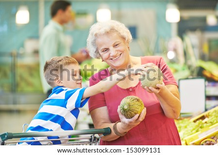 Adult Woman With Child Choosing Melon Fruit During Shopping At Vegetable Supermarket