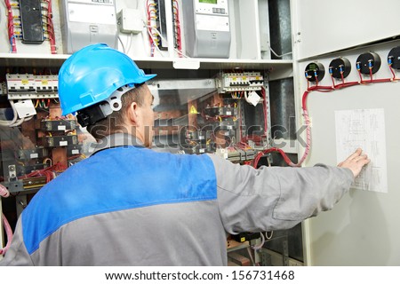 electrician builder at work checking wire with drawing inspecting high voltage power electric line distribution fuseboard