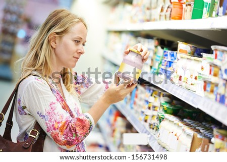 Young woman choosing fresh milk produces at shopping in dairy supermarket store