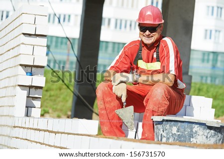 Portrait of Builder construction mason worker bricklayer with trowel putty knife outdoors