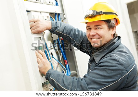 One Electrician Builder At Work Installing Energy Saving Meter Into Electric Line Distribution Fuseboard