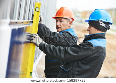 Plasterer builder worker with level examining granite stone marble facade works