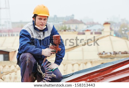 roofer builder worker with pulverizer spraying paint on metal sheet roof