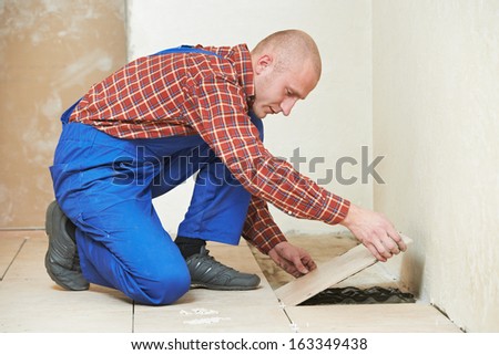 professional tiler builder worker installing home floor tile at repair renovation work