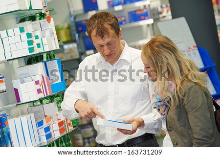 cheerful pharmacist chemist man worker standing at pharmacy drugstore desk with colleague