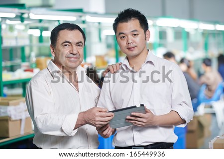 caucasian businessman manager and male chinese worker man in china factory manufacturing production