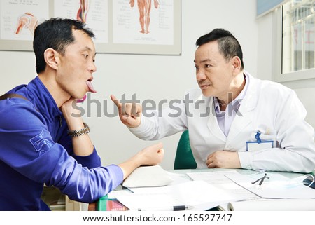 Chinese adult asian male doctor in clinic during tongue diagnosis