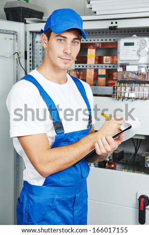 Young adult electrician builder engineer inspecting electric counter equipment in distribution fuse box