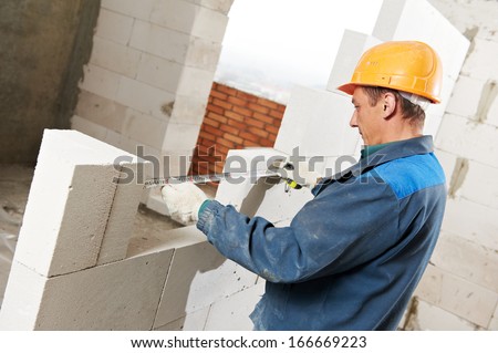 construction mason worker bricklayer installing calcium silicate brick during indoor wall creation