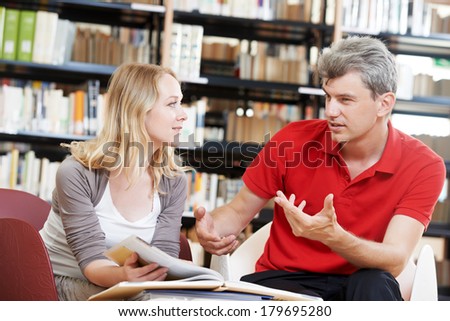 Two young adult peoples reading discussing book in a library