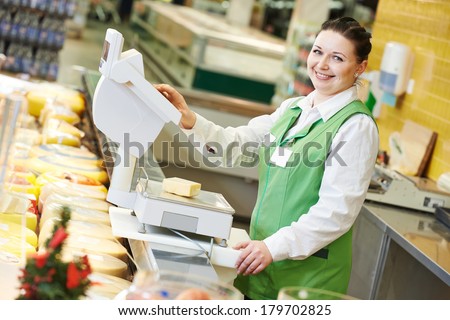 Smiling saleswoman assistant in supermarket working with scales balance to pregnant female customer during shopping at store