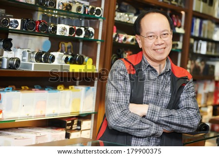 Assistant seller help buyer by demonstrating digital photo camera at shop store