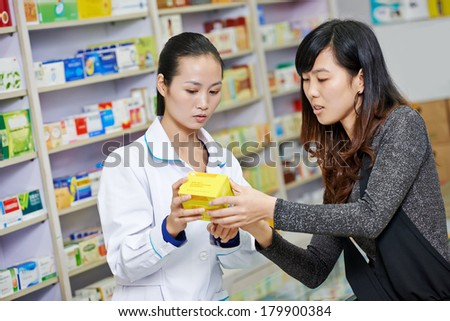 Two cheerful chinese pharmacist chemist woman standing in china pharmacy drugstore Two cheerful chinese pharmacist chemist woman standing in china pharmacy drugstore