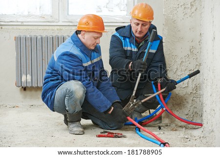 two repairman engineer installing house heating system at interior construction site