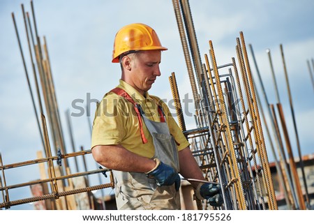 builder worker knitting metal rods bars into framework reinforcement for concrete pouring at construction site