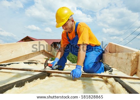 construction roofer carpenter worker hammering wood board with hammer and nail on roof installation work