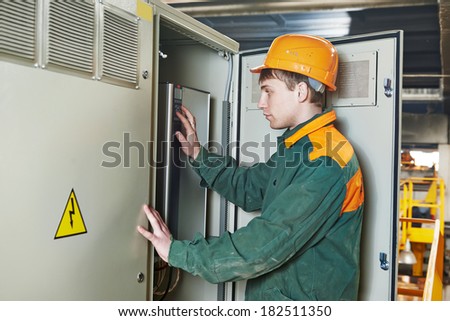 Young adult electrician builder engineer switching actuator equipment in distribution fuse box