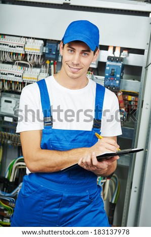 Young adult electrician builder engineer inspecting electric counter equipment in distribution fuse box