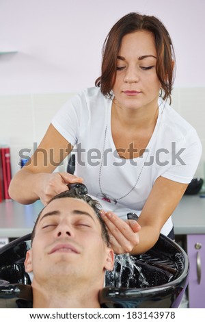 Washing man client hair in beauty parlour hairdressing salon