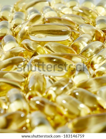 Heap of yellow round pharmacy medicine antibiotic capsule pills with omega-3 fish fat oil. Shallow DOF