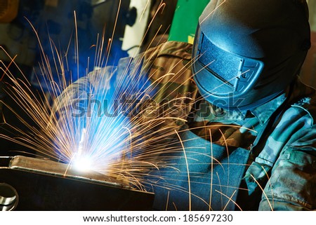 welder working with electrode at semi-automatic arc welding in manufacture production plant