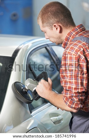 auto mechanic worker polishing car body at automobile repair and renew service station shop by power buffer machine