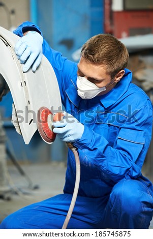 auto mechanic worker polishing bumper of car body at automobile repair and renew service station shop by power buffer machine